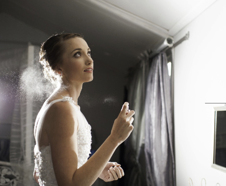 bride in front of mirror spraying perfume